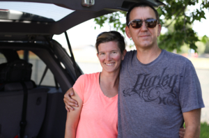 A couple - Holly and Craig - pose by their vehicle.